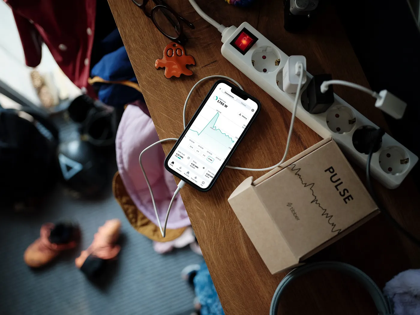 Telefoon met de Tibber-app naast de verpakking van de Tibber Pulse