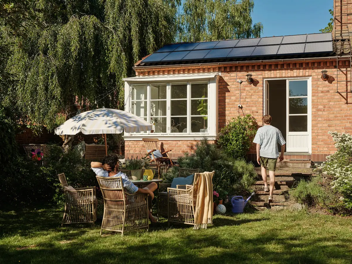 Woonhuis met zonnepanelen op het dak en een tuin met zitgroep